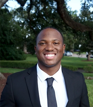 Brent York headshot taken outdoors, he wears a dark suit.